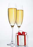 Glasses of sparkling champagne with red gift box