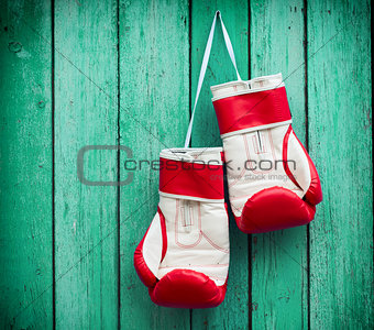 pair of red boxing gloves hanging on a nail on a background of g
