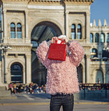 modern girl in Milan, Italy hiding behind red shopping bag