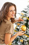 Portrait of smiling young woman decorating christmas tree