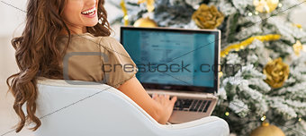 Smiling young woman using laptop near christmas tree