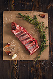 Uncooked pork ribs on paper with thyme and garlic 