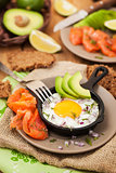 Fried egg, avocado and smoked salmon in frying pan 