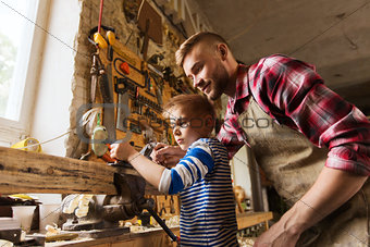 father and son with plane shaving wood at workshop