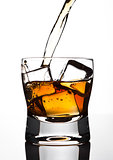 Pouring whiskey to the glass with ice cubes