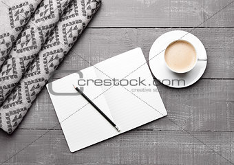 Cup of cappuccino with grey wool scarf and diary