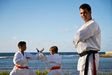 Portrait Of Confident Karate Trainer Watching Children Fight