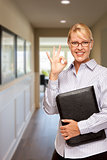 Woman with Folder and Okay Hand Sign In Hallway of House