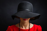 The beautiful woman in a black hat with the wide fields closing eyes and  nose