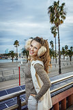 smiling trendy tourist woman in earmuffs in Barcelona, Spain