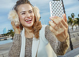 woman on embankment in Barcelona taking selfie with smartphone