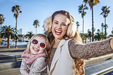mother and daughter on embankment in Barcelona taking selfie