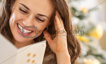 Smiling young woman reading christmas postcard