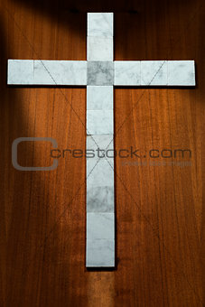 White Marble Cross on a Wooden Background