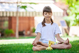 Little girl relaxing while sitting on grass, with small ducklings