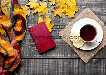 Cup of tea with lemon with scarf and autumn leaves