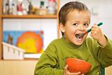 Happy boy eating breakfast - cereals and milk