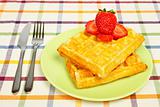 Waffles and strawberries on green plate
