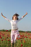 Girl jumps over poppy field