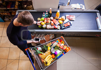 Young man before checkout in supermarket