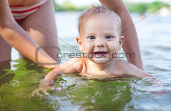 Young woman and little son playing in water on summer day
