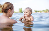 Young woman and little son playing in water on summer day