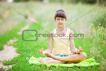 Young girl relaxing while sitting in lotus position outdoors