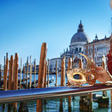 Closeup on Venetian mask in hand of woman on embankment