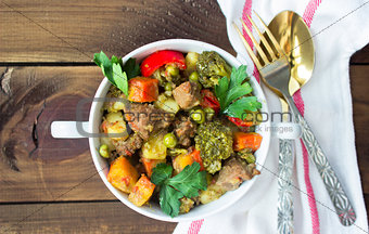 served beef meat stewed with vegetables in ceramic pot on wooden background