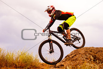Professional Cyclist Riding the Bike Down Rocky Hill. Extreme Sport Concept. Space for Text.