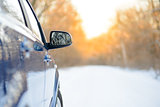 Close up Image of Side Rear-view Mirror on a Car in the Winter Landscape with Evening Sun