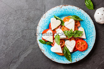 Caprese salad with tomatoes, cheese hearts, basil. Valentine day menu