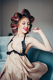 Beauty portrait of young woman wearing curlers and vintage lingerie.