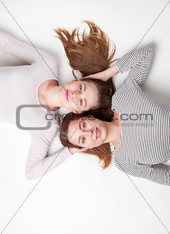 Portrait of happy sisters lying on the floor 