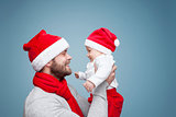 Father with baby boy wearing Santa hats celebrating Christmas