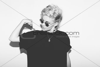 Stylish fashion sexy blonde bad girl in a black t-shirt and rock sunglasses. Dangerous rocky emotional woman.   white toned.  background, not isolated