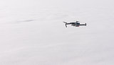 Small modern drone hovering against white snow