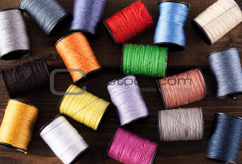 Colorful cotton reels scattered on dark wood