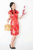 Oriental female in red qipao holding gift basket
