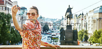 happy woman taking selfie with cellphone in Prague
