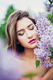 Portrait of young beautiful woman posing among lilac. Closed eyes.