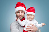 Father with baby boy wearing Santa hats celebrating Christmas