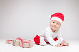 Adorable baby wearing a Santa hat opening Christmas presents