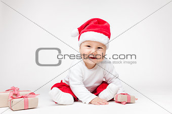 Adorable baby wearing a Santa hat opening Christmas presents