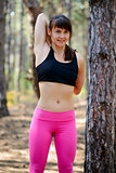 Young Fitness Woman Stretching in the Pine Forest. Female Runner Doing Stretches . Healthy Lifestyle Concept.