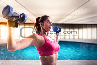 Muscular woman is training with weights dumbbells