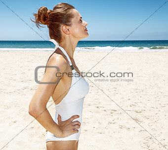 Relaxed woman in white swimsuit at sandy beach