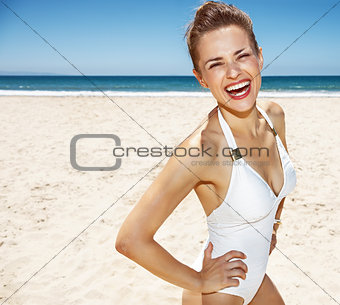Portrait of smiling woman in white swimsuit at sandy beach