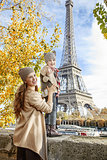 mother and child travelers handwaving on embankment in Paris