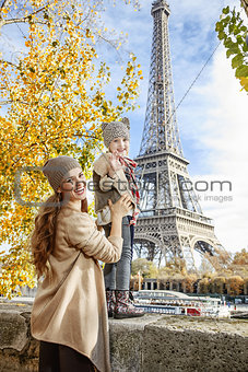 mother and child travelers handwaving on embankment in Paris